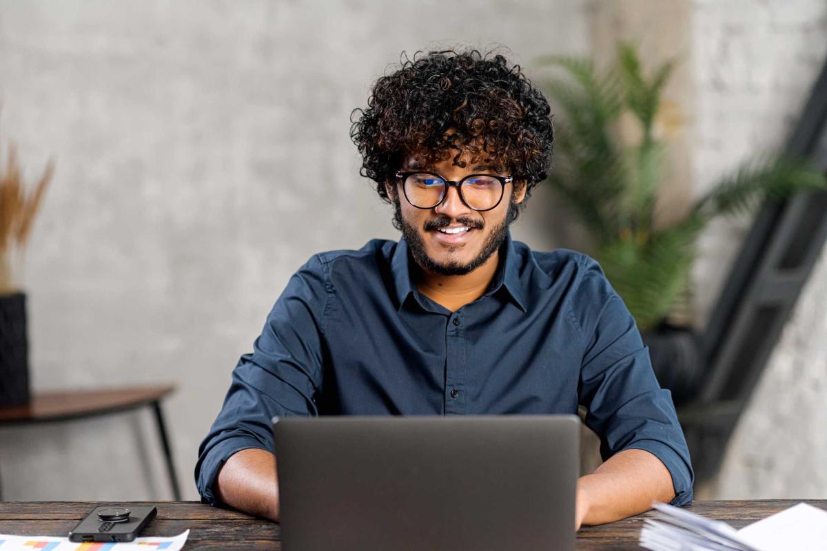 A young man looking at his laptop with a smiling face